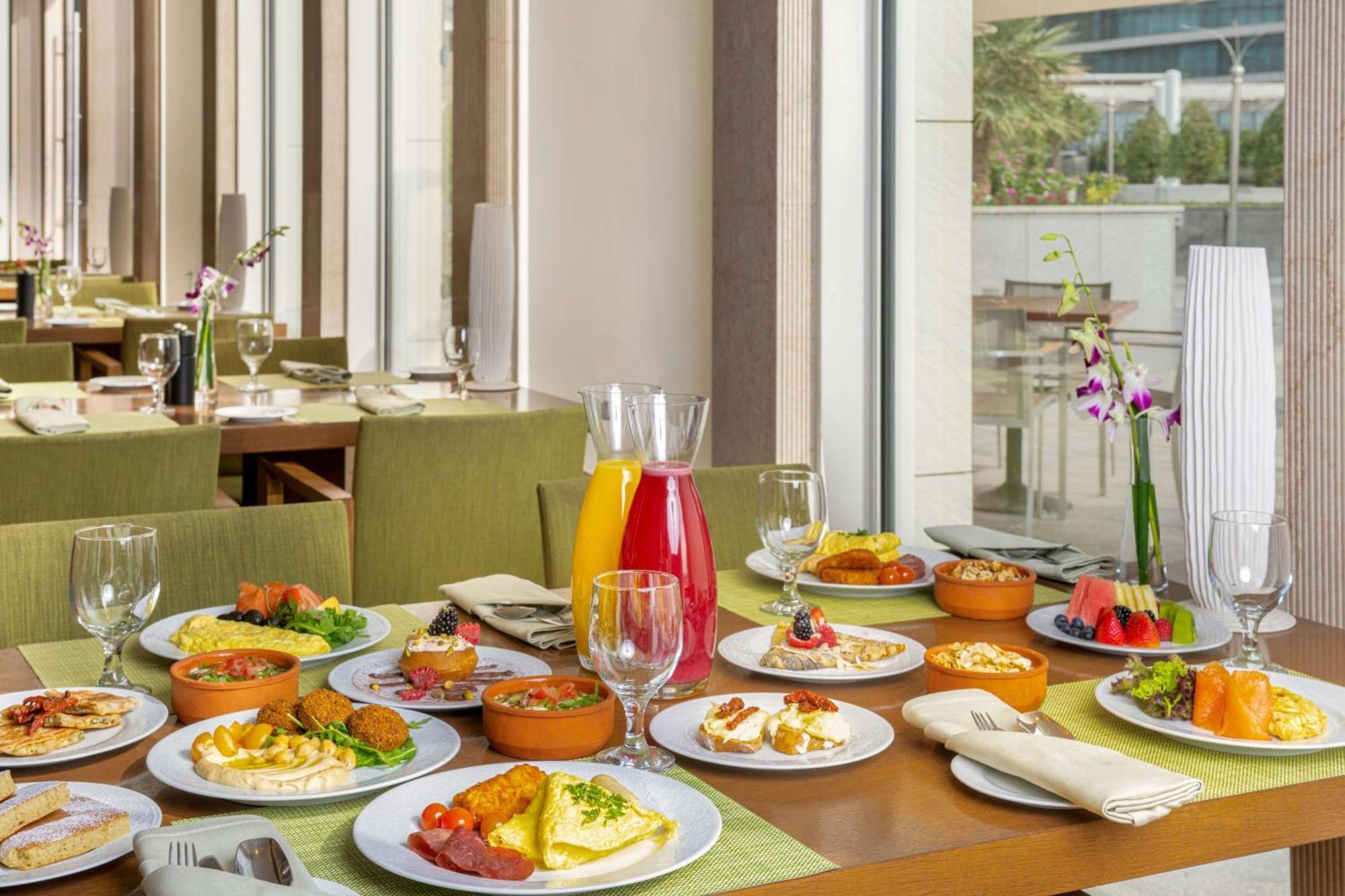 Hilton Riyadh Hotel&Residences Exterior foto The photo showcases a beautifully arranged dining table filled with a variety of dishes. There are multiple plates featuring an assortment of foods, including salads, appetizers, and main courses, presented in a vibrant and appetizing manner. Additio